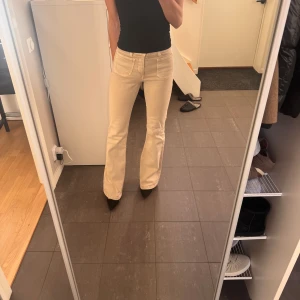 Beige bootcut byxor - Snygga beige bootcut byxor med medelhög midja. Perfekta för en stilren look. Byxorna har en klassisk design med fickor fram och bak.