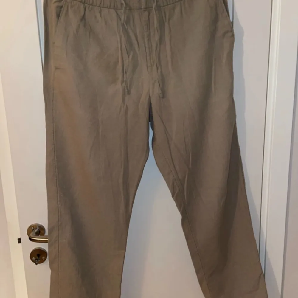 Säljer ett par bekväma beige linne byxor från H&M i regular fit. Byxorna har elastisk midja med snörning för extra komfort. Perfekta för en avslappnad stil.. Farkut & Housut.