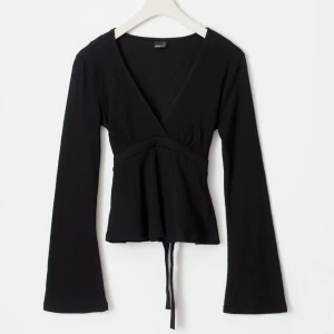 Svart blus - Snygg svart omlottopp från Gina tricot med långa ärmar och knytband i midjan. Använd en gång!💓