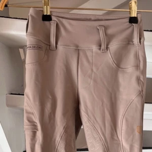 Beige ridbyxor från Maya Delorez - Snygga beige ridbyxor från Maya Delorez. Byxorna har en tight passform och är perfekta för ridning. Strl barn/ungdom 2XS.Byxorna är som nyskick,  sparsamt använda.