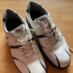 Ecco Golfskor Vita - Ecco golfskor i vitt med svarta detaljer. Skorna är endast använda en gång så är i gott skick. En rejäl och stadig sko som tyvärr inte passar min fot.   Storlek 37