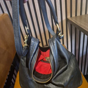 Jättesnygg handgjord väska - Handgjord väska av Sofia Agardtson. I exklusivt, mjukt anilinläder. Ett kortare handtag och en längre axelrem. Inuti väskan finns tre öppna fickor, en ficka med blixtlås samt en nyckelhållare. Väskan stängs med hake och D-ring. Super kvalitet