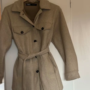 Höst Kappa - Kappa från Zara, storlek xs. Använd fåtalet gånger och i mycket fint skick. Man kan knäppa den men också ha den uppknäppt med bälte. 