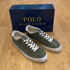 Gröna sneakers från Polo Ralph Lauren - Säljer ett par snygga gröna sneakers från Polo Ralph Lauren. De är i mocka med vita snören och en vit sula. Skorna är i bra väldigt bra skick och är nästan aldrig användna och dom kommer med originalkartong.