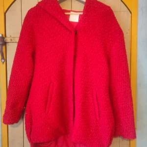 Röd stickad jacka från Zara - Säljer en superfin röd stickad jacka från Zara. Den är från deras vinterkollektion och har en mysig huva. Jackan är långärmad och har praktiska fickor på sidorna. Perfekt för kalla dagar när du vill vara både varm och stilren. 🧣