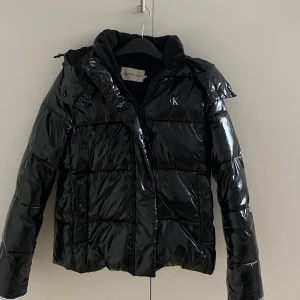 Calvin Klein - Calvin Klein high shine puffer i storlek s. Köpt för ett år sen för 2195kr och säljer för 1500. Knappt använd och i ny skick. Säljer då jag aldrig använder den och den inte längre är min stil. Skön och varm jacka till vintern