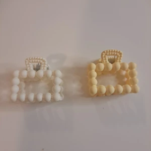 Vita och beige pärlade hårklämmor - Två hårklipp i pärlor, en i vitt och en i beige.  De har ett rektangulärt format. 1 för 10 - 2 för 20