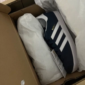 Adidas Skor Gazelle - Säljer dessa helt nya Adidas Gazel i mörktblått. De är endast provade 1 gång och prislappen sitter kvar. Storlek 38 2/3 Pris går att diskutera💕
