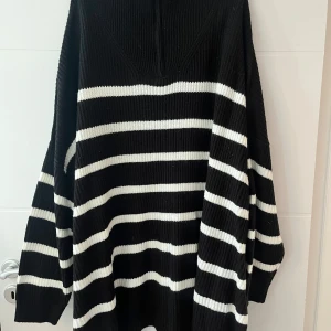 Svart randig tröja med dragkedja  - Svart randig tröja med dragkedja.  Storlek: EU 54-56