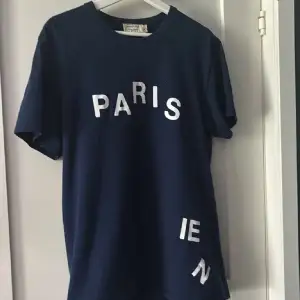 Säljer en snygg mörkblå t-shirt från Maison Kitsuné med texten 'PARISIEN' i vitt på framsidan. Den är i storlek M. Säljer helt enkelt för jag har ingen användning för den.  Pris flexibelt