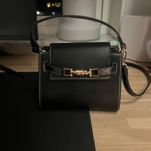 Handväska  - Säljer min axel väska från Nakd, har gjort två egna hål i bandet just för att man ska kunna ha väskan högre upp, se bild! Men absolut inget man tänker på 🫶🏽