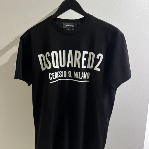 Svart t-shirt från Dsquared2 - Säljer en helt ny svart t-shirt från Dsquared2 med tryck 'Ceresio 9, Milano' i vitt på framsidan. Perfekt för en casual look eller att styla upp för en fest. T-shirten är kortärmad och gjord i mjuk bomull. 