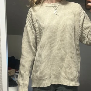 Beige stickad tröja från Clifton - Säljer en stilren beige stickad tröja från Clifton. Tröjan har en klassisk design med ribbade muddar och rund hals. Perfekt för kyligare dagar och enkel att matcha med olika outfits. För stor på mig