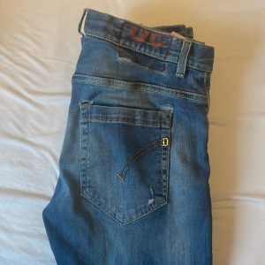 Blå jeans med slitningar - Snygga blå jeans med slitningar och en cool tvätt. De har en klassisk femficksdesign och knappgylf. Perfekta för en avslappnad stil.