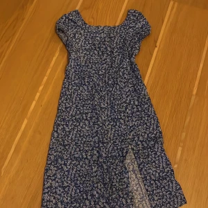 Blommig klänning från H&M - Söt blommig klänning från H&M i blått och vitt. Klänningen har korta ärmar och ett fint blommönster. Perfekt för sommarens varma dagar.