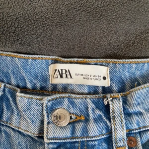 Högmidjade jeans från Zara - Blåa jeans i bra skick från Zara. Har inga defekter. Byxorna är storlek 34 och relativt korta i benen, passar bäst om man är 160-165. Har en slitning vid knäet.