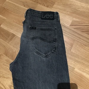 Grå jeans från Lee - Snygga grå jeans från Lee med klassisk femficksdesign. De har en rak passform och är perfekta för en avslappnad stil. Tillverkade i slitstarkt denim med en bekväm midwaist.