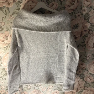 Grå stickad offshoulder tröja - Mysig grå stickad tröja med offshoulder-design. Perfekt för kyliga dagar med sin mjuka och bekväma passform. Den ribbade kanten ger en extra touch av stil.