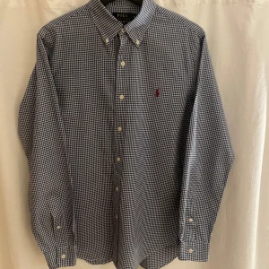 Ralph Lauren skjorta - Snygg rutig skjorta från Ralph Lauren i svart och vit med klassisk krage och knappar framtill. Skjortan har en broderad logotyp på bröstet och är i slim fit. Perfekt för en stilren look. Den är i grymt skick och i storlek S-M