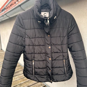 Svart täckjacka från Cubus! - Svart figursydd täckjacka med fickor fram, dragkedja och knappar i storlek M från Cubus. Sparsamt använd och i mycket fint skick. 