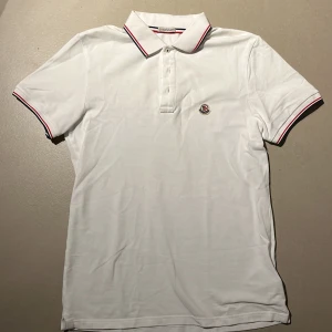 Vit Moncler piké  - Säljer nu denna vita monclear pikén i storlek S. Den passar bäst runt 165-175. Den har 3 knappar längst upp vid kragen. Nypris är runt 1500kr. Originella påsen och kortet tillkommer. Är i väldigt bra skick, inga defekter eller fläckar eller liknande. tveka inte att fråga om ni undrar något, pris är diskuterbart vid snabbköp. 