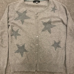 Grå kofta med stjärnor från Mark Adam New York  - Säljer min super super fina gråa kashmir kofta köpt i New York för inte så länge sedan på grund av att den inte kommer till användning. Har inte alls använt mycket och har därför inga stora defekter förutom att den nedersta knappen gått av. Köpt för 900 säljer för 450, priset kan diskuteras. 