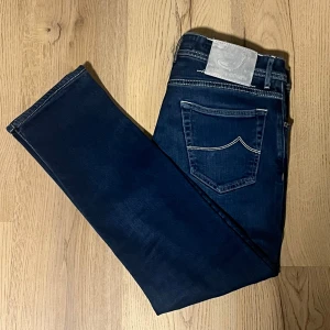 Jacob Cohen jeans  - Snygga mörkblå jeans från Jacob Cohen med klassisk femficksdesign och kontrastsömmar. Tillverkade i Italien med högkvalitativt material för en stilren look. Perfekta för en avslappnad men ändå elegant stil.