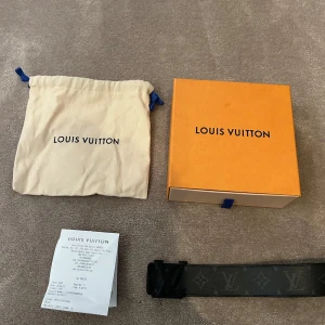 Svart bälte från Louis Vuitton - Snyggt svart bälte från Louis Vuitton med det klassiska monogrammönstret. Bältet har en elegant design med en svart spänne som ger en stilren look. Perfekt för att lyfta vilken outfit som helst. I storleken 98 cm.