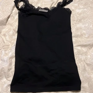 Svart linne från Soaked in Luxury - Snyggt svart linne från Soaked in Luxury med spetsdetaljer vid axelbanden och halsringningen. Linnet är i ett litet mer tjockare material och rätt stretchigt!🥰