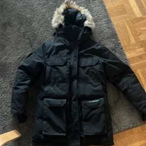 Svart vinterjacka från Canada Goose - En vintage canasta goose jacka i bra skick med äkta päls och riktigt dun är inte helt säker om den är äkta men ser jättebra ut och är tjock och tung priset är inte hugget i sten så lägg bud så avgör vi vad som är rätt pris