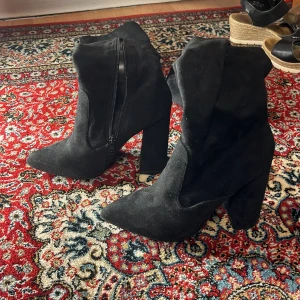 Svarta mockastövlar med klack - Snygga svarta stövlar i mocka med hög klack och dragkedja på sidan. Perfekta för en stilren look.