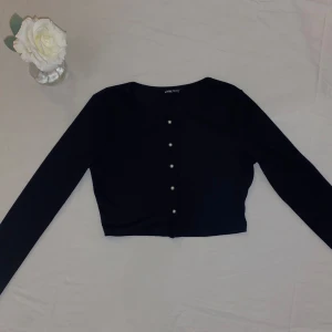 Svart långärmad topp med pärlknappar - Fin svart långärmad topp med pärlknappar framtill. Tröjan är knappt använd och är i fin skick. Storlek är M, men passar personer med XS/S.