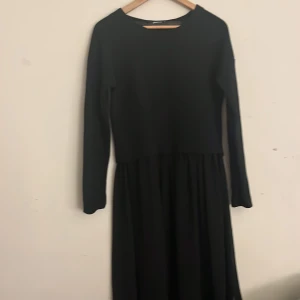 Svart klänning från Gina Tricot - Elegant svart klänning från Gina Tricot med långärmad design. Perfekt för en stilren look. Klänningen har en klassisk passform och är tillverkad i ett bekvämt material.