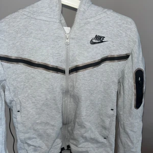 Grå Nike tech  - Säljer en grå Nike tech då den inte längre kommer till användning. Den är i gott skick och priset är öppet för diskussion! Stoleken är M i barn storlek