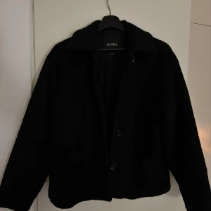 Svart jacka från Monki - Säljer en stilren svart jacka från Monki i storlek XXS. Jackan har en klassisk design med knappar framtill och långa ärmar. Perfekt för en minimalistisk look.