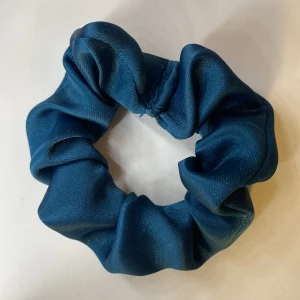 Blå scrunchie i satin - Snygg blå scrunchie i satin som ger en lyxig känsla. Perfekt för att sätta upp håret med stil eller som en fin accessoar runt handleden. Detta är inte samma som den andra annonsen!