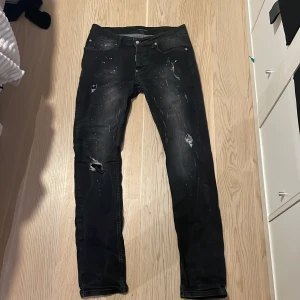 Svarta jeans från Dsquared2 - Snygga svarta jeans från Dsquared2 med slitna detaljer och en cool, distressed look. Perfekta för en edgy stil. De har en klassisk femficksdesign och knappgylf.