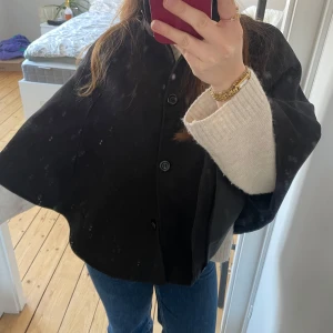 Svart kappa/poncho/cape  - Säljer en stilren svart kappa med knappar framtill. Den har en lös passform och är perfekt för höst och vår. Jackan är enkel att matcha med olika outfits och ger en elegant touch.❣️❣️