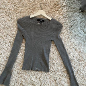 Grå ribbad tröja - Säljer en stilren grå ribbad tröja från Forever 21. Tröjan har en tight passform och långa vida ärmar. 