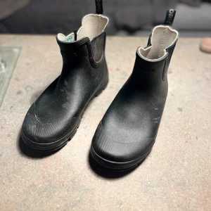 Svarta låga gummistövlar från Tretorn - Säljer ett par svarta Tretorn gummistövlar i storlek 36. Stövlarna är designade för att vara hållbara och har en grov sula som ger bra grepp på olika underlag. Praktiska att använda under regniga dagar eller i lerig terräng.  Skick: Mycket bra skick.   Nypris: 500 SEK
