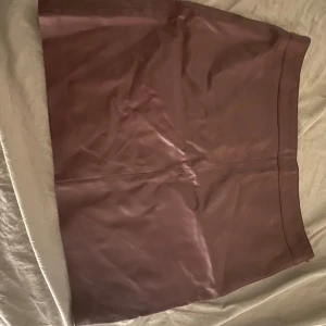 Brun (faux) skinnkjol - Snygg brun skinnkjol i kort modell. Perfekt för att ge din outfit en cool touch. Kjolen har en stilren design utan extra detaljer.