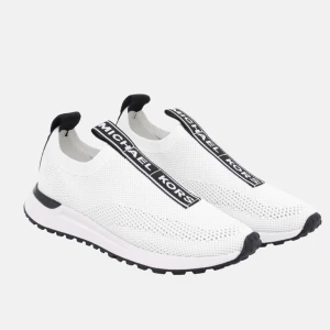 Vita sneakers från Michael Kors - storlekar mellan 36-41 (stora i storlekarna) Säljer ett par snygga vita sneakers från Michael Kors. De är tillverkade i ett stickat material som gör dem både lätta och bekväma. Skorna har en svart sula och svarta detaljer, inklusive en rem med Michael Kors-loggan över ovansidan. Perfekta för både vardag och träning!