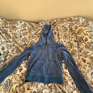 Blå hoodie från Juicy Couture - Säljer en snygg och bekväm blå hoodie från Juicy Couture. Den är i mjukt material och har en dragkedja framtill samt en luva. Perfekt för en avslappnad stil eller mysiga dagar hemma. Hoodien har långa ärmar och en normal passform. Köp direkt eller ge prisförslag 💙