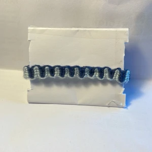  Armband -  Handgjort armband i bomullsgarn, man kan ändra storleken 14-25, 1 cm brett. Armbandet är ljusblått och mörkblått.