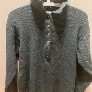 Stickad tröja  - En mörkgrön stickad tröja med knappar längs med kragen. Använd sällan och är i fint skick! Från Foxtrot original by Hennes & Mauritz