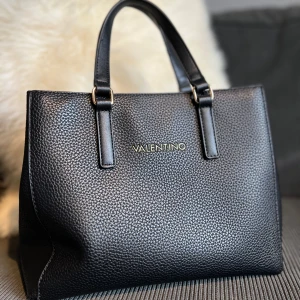 Valentino väska - En super snygg väska ifrån valentino. Använd fåtal gånger och där med ser ny ut. Ett längre band medföljes. Ny priset ligger på 1045kr. 🤍