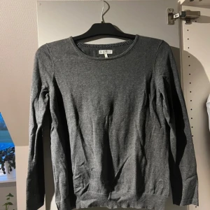 Grå stickad tröja från Gant - Säljer en snygg och bekväm grå stickad tröja från Newhouse. Tröjan har en enkel design med långa ärmar och rund hals. Perfekt för höst och vinter! 🧶