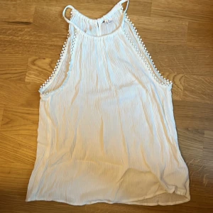 Vit ärmlös topp med spetsdetaljer - Säljer en söt vit linne  i storlek S. Toppen har fina spetsdetaljer längs sidorna och en liten öppning i ryggen❤️