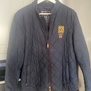 Morris Trenton quilted jacket - Säljer en snygg och stilren quiltad jacka från Morris i storlek M. Jackan är mörkblå och har dragkedja framtil plus två fickor med dragkedja. Broderat emblem på bröstet. Fint skick! Perfekt för höst och vår Nypris 2200kr