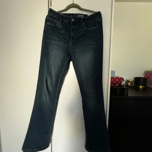 Mörkblå jeans från Denim - Säljer ett par mörkblå jeans från Denim i storlek 42 (dam L). De är i bra skick och har en klassisk femficksdesign med knapp och dragkedja framtill. Perfekta för vardagsbruk!